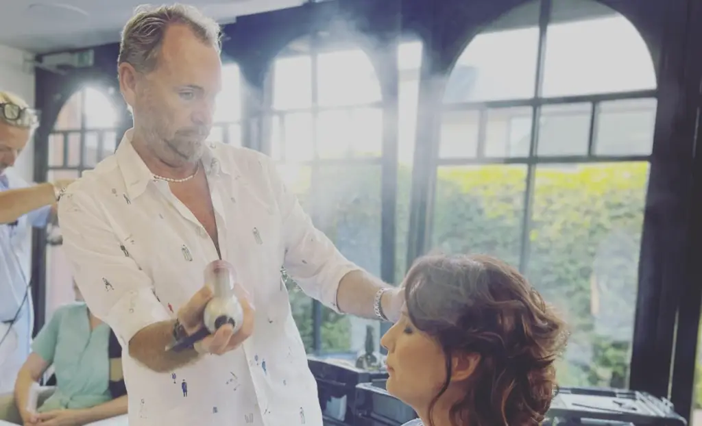 Kapper die kapsel afwerkt met haarlak in kapsalon